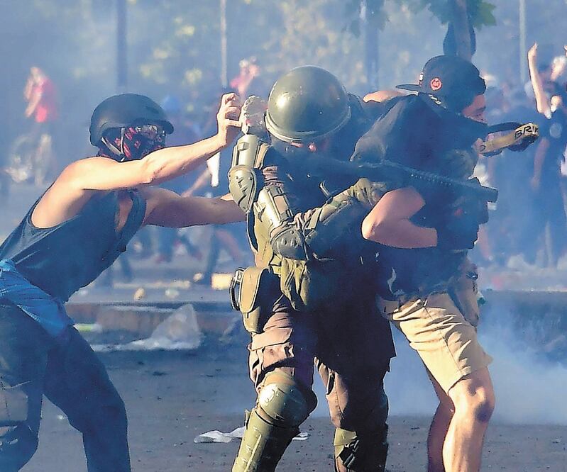 Un manifestante golpea a un agente del orden durante las protestas contra el gobierno de Sebastián Piñera, en Santiago. Foto: MARTIN BERNETTI. AFP
