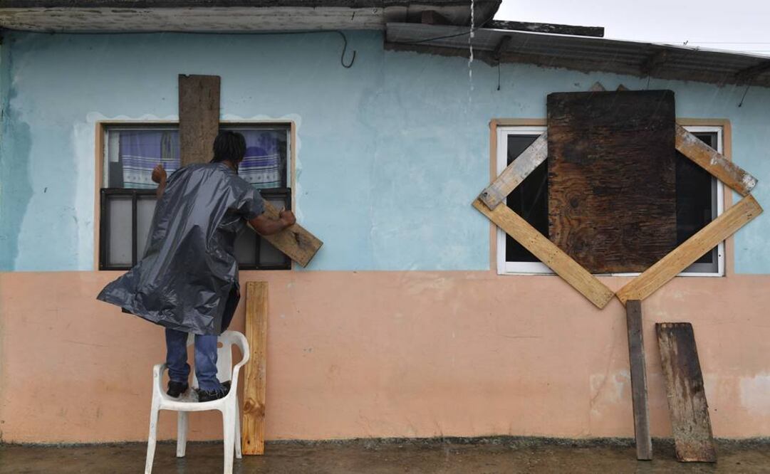 Un hombre cubre las ventanas de su casa en Tecolutla. (AFP)