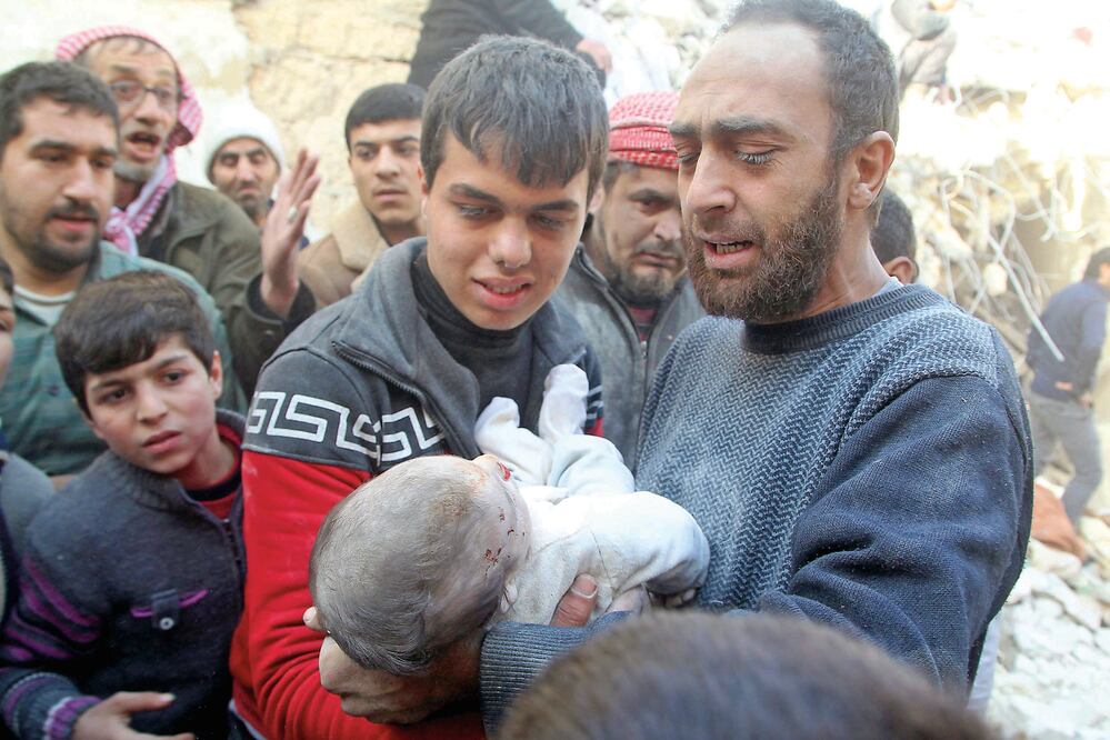 Un hombre sirio toma en brazos el cuerpo de un bebé que murió en los bombardeos rusos y de las fuerzas del gobierno de Al-Assad, en un barrio rebelde de Aleppo, donde aún hay gente bajo los escombros de las casas (ABDALRHMAN ISMAIL. REUTERS)