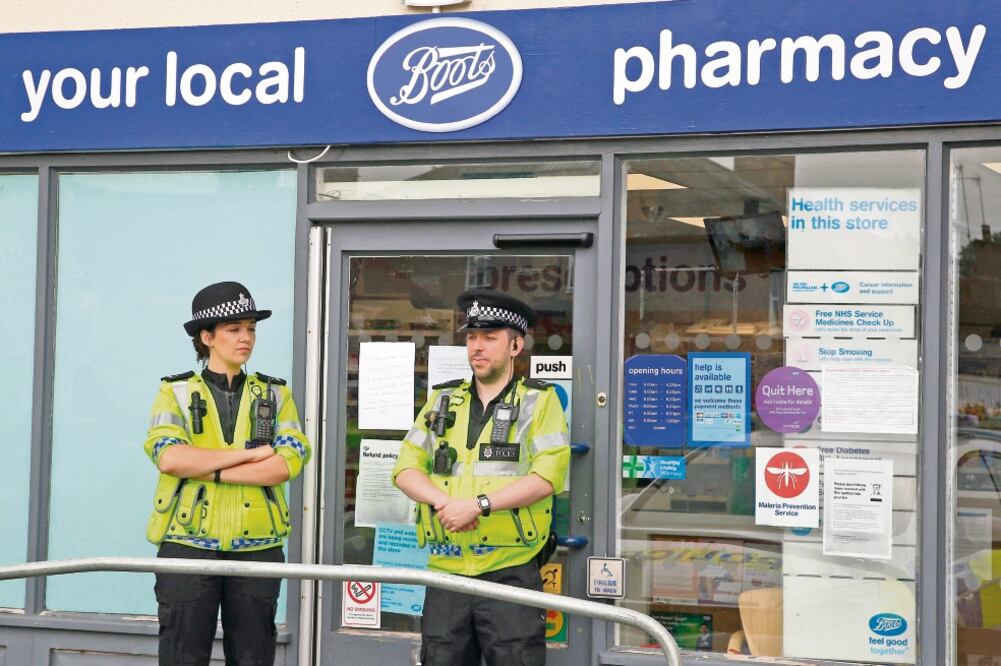 Oficiales de policía montan guardia afuera de una farmacia en Amesbury, localidad donde dos personas se encuentran graves a consecuencia de un agente neurotóxico (GEOFF CADDICK. AFP)
