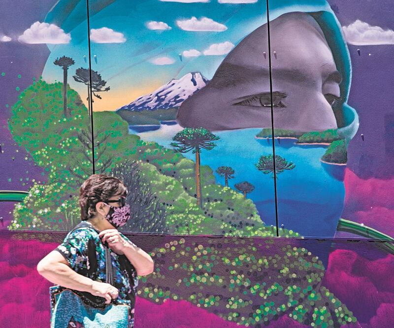 Una chilena con cubrebocas pasa junto a un mural restaurado en el paseo Bandera, en Santiago. La nueva cepa del Covid-19 llegó al país. Foto: ALBERTO VALDÉS. EFE