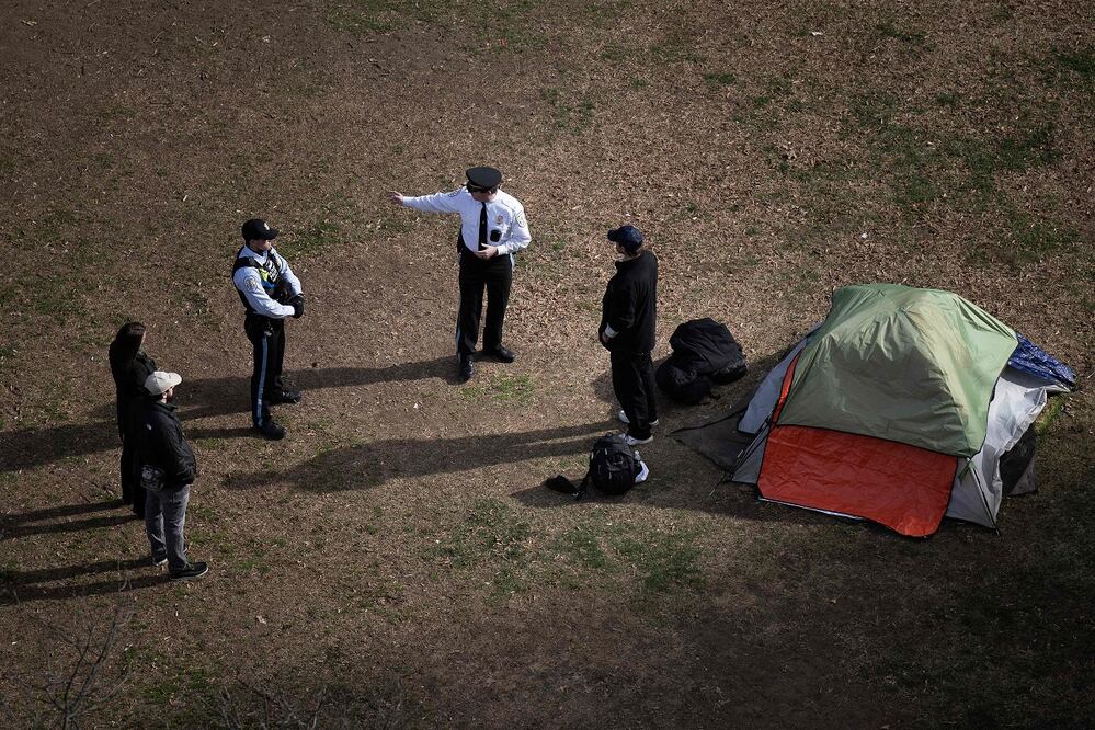 Policías hablan con una persona sin hogar que se niega a irse, en la Plaza McPherson Square, a dos cuadras de Washington, DC. FOTO: BRENDAN SMIALOWSKI. AFP