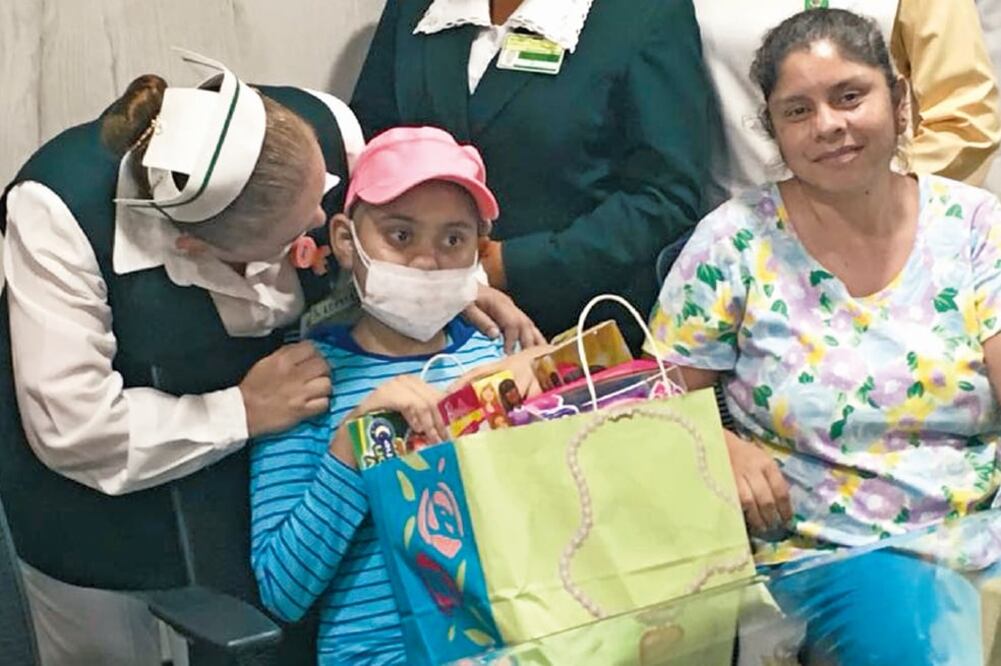 Sosteniendo unos regalos, Gabriela Sarahí, de 12 años, acompañada de una enfermera del Instituto Mexicano del Seguro Social y de su madre, Gabriela Ibarra Carrillo, luego de haber sido dada de alta (CORTESÍA IMSS)