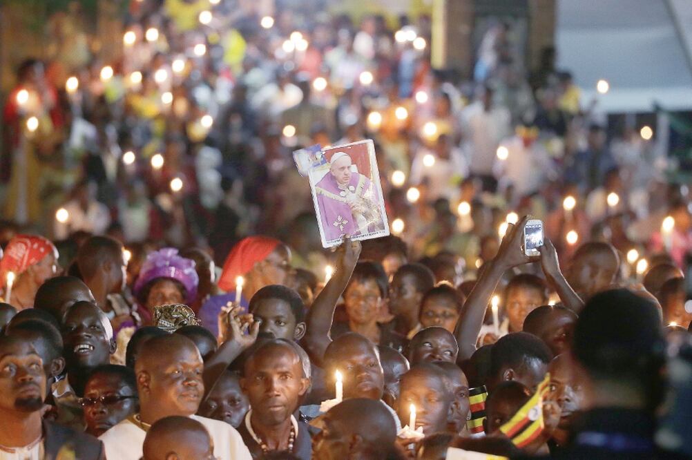Ugandeses sostenían ayer velas e imágenes del papa Francisco, quien encabezó una ceremonia en el santuario católico de Munyono (ANDREW MEDICHINI. AP)