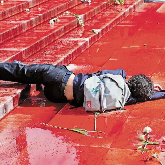 Un integrante del grupo de activistas de Extinction Rebellion (XR) yace en el suelo en medio de un charco de sangre falsa, durante una protesta, en París. FRANCOIS GUILLOT. AFP