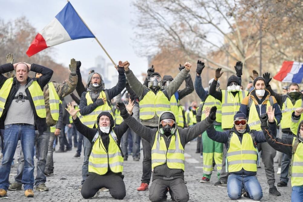 Manifestantes gritan consignas cerca del Arco del Triunfo, en París. La policía disparó gases lacrimógenos y cañones de agua contra los chalecos amarillos, ayer. (CHEN YICHEN. XINHUA)