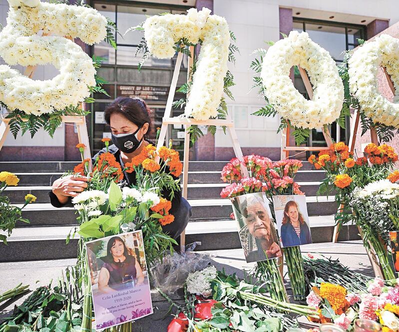 Elda Martínez, con la Federación Laboral de Los Ángeles, en un monumento en honor a 5 mil 700 residentes muertos por Covid. MARIO TAMA. AFP