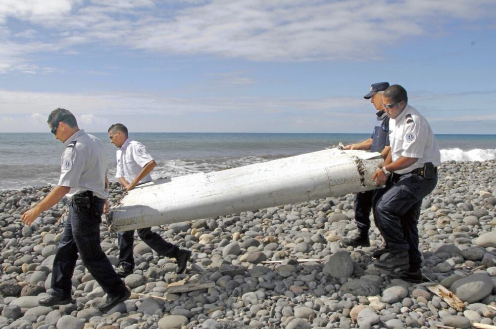 Policías trasladan el resto del ala de un avión no identificado en La Reunión, Francia, en esta imagen del miércoles 29 de julio. Las autoridades indagan si el fragmento pertenece al vuelo MH370 (RAYMOND WAE TION. EFE)