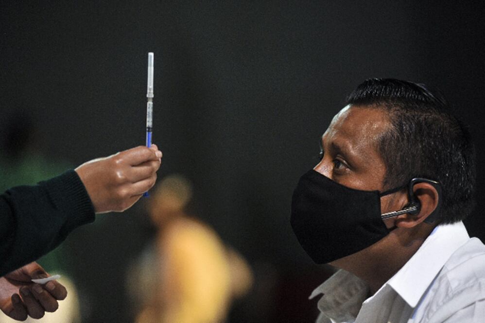 Trabajadora de la salud muestra a un hombre una dosis de una vacuna antiCovid. Foto: Xinhua