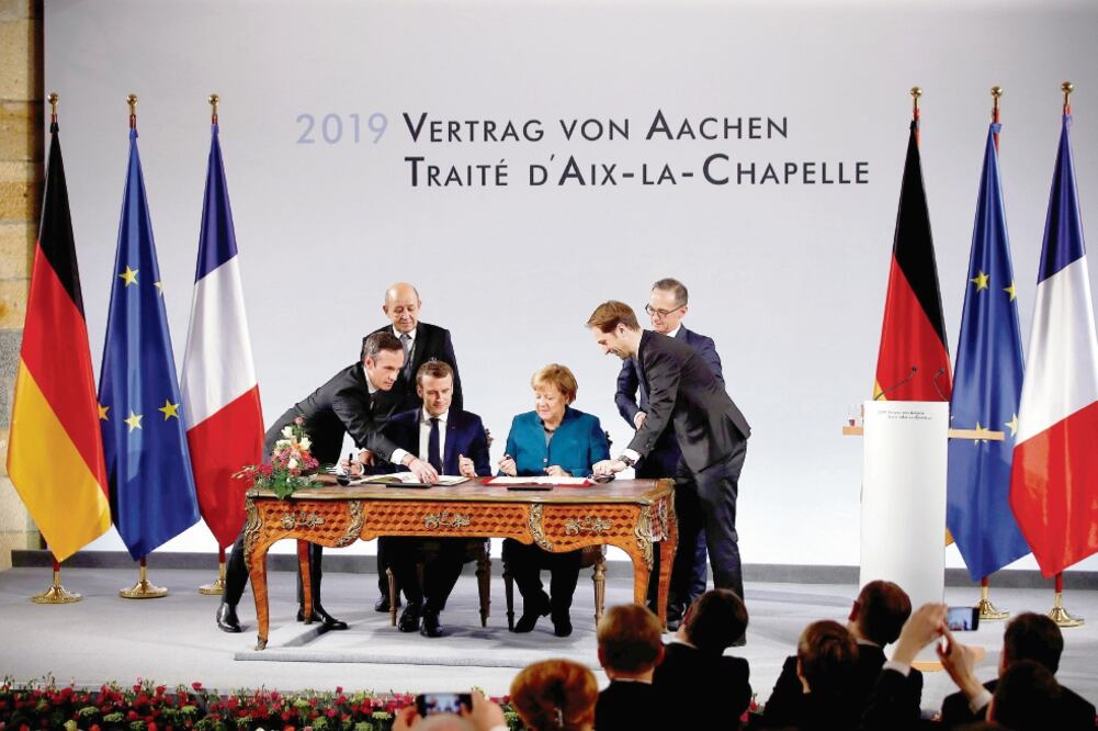 La canciller alemana Angela Merkel y el presidente francés Emmanuel Macron (sentados), al firmar ayer el nuevo acuerdo de cooperación bilateral, en la localidad germana de Aachen. (ARNULFO FRANCO. AP)