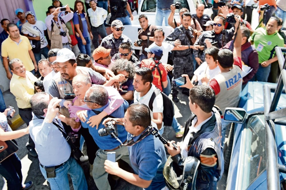 Luego de arribar a las oficinas de la estación Radio Notisur, policías obligaron a subir a el locutor Gamaliel García y dos comunicadores más a una de las camionetas, pero sus compañeros lo impidieron (DASSAEV TÉLLEZ. EL UNIVERSAL)