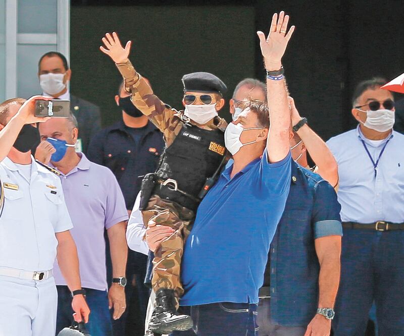 El presidente brasileño, Jair Bolsonaro, carga a un niño vestido como militar, durante el mitin que encabezó ayer en Brasilia. Foto: SERGIO LIMA. AFP