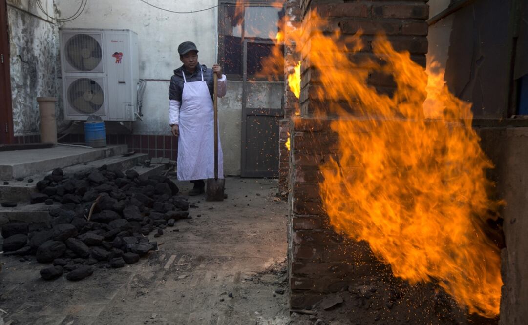 Un trabajador aguarda para palear más carbón en las estufas de una cocina en la aldea Liuminying en Beijing, China. Foto: AP