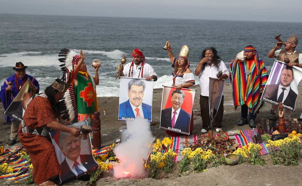 Un grupo de chamanes y curanderos sostienen imágenes de varios lideres mundiales durante un ritual de fin de año este lunes, frente al océano Pacífico en Lima (Perú). (29/12/25) Foto: EFE