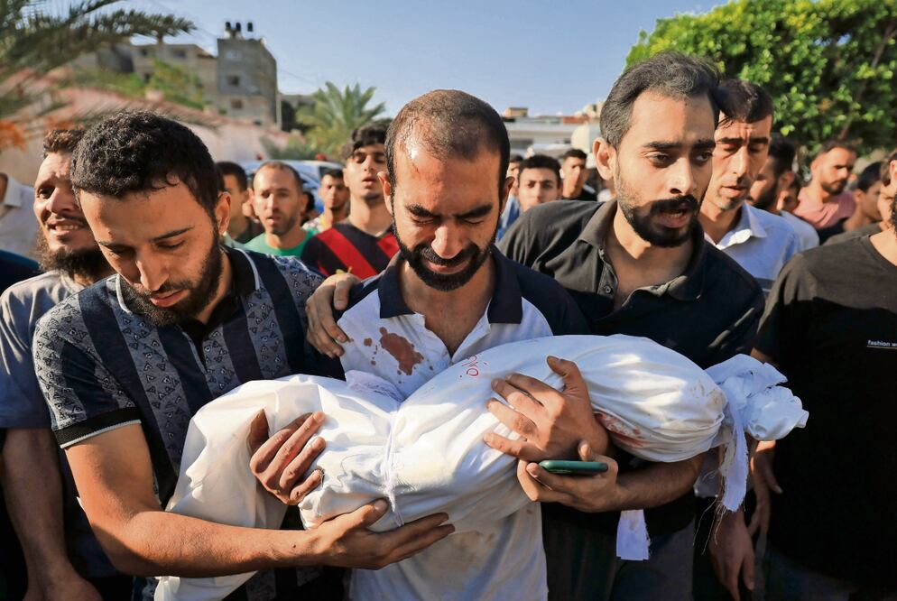 El padre de un niño que murió cuando un ataque aéreo israelí alcanzó su casa lleva su cuerpo durante su funeral en Khan Younis. Foto: AFP