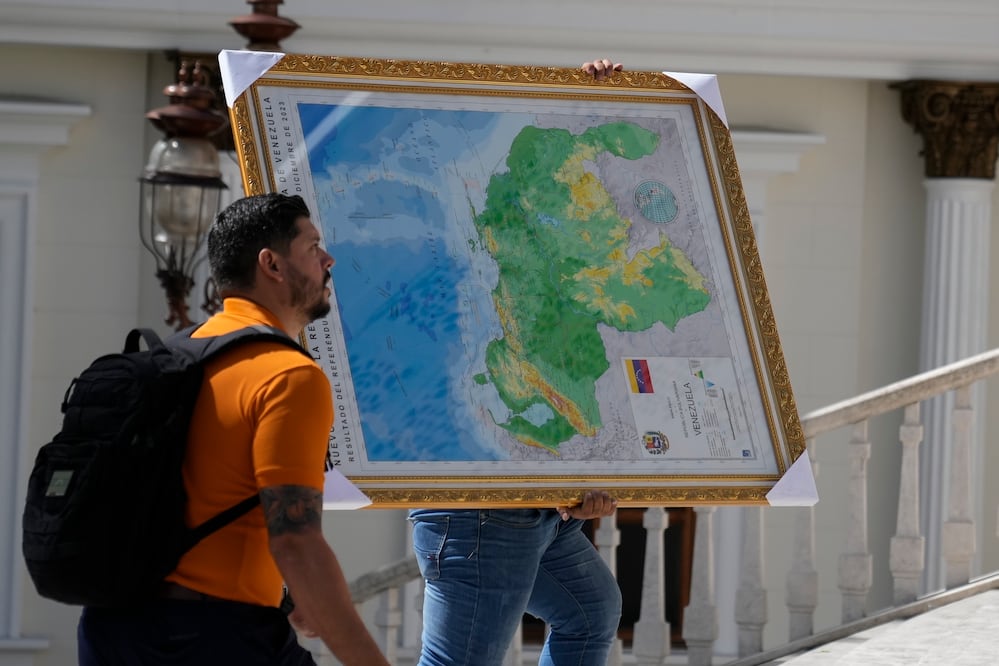 Un hombre lleva el "nuevo mapa de Venezuela" con el territorio del Esequibo, una gran franja de tierra administrada y controlada por Guyana pero reclamada por Venezuela, al edificio de la Asamblea Nacional en Caracas, Venezuela. Foto: AP Photo/Ariana Cubillos