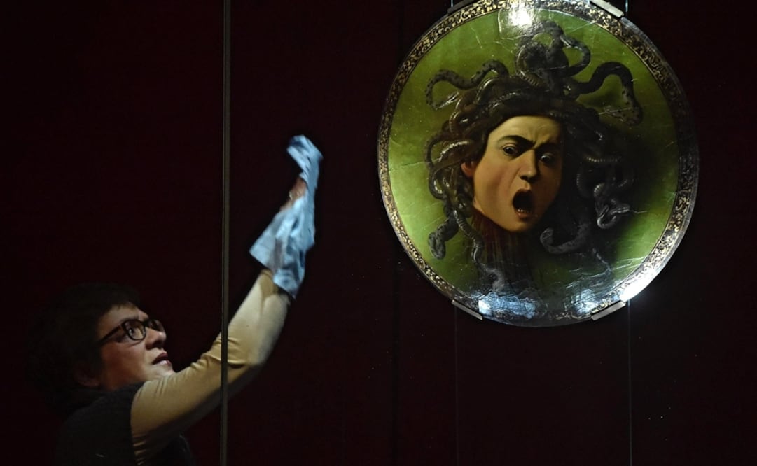 Una trabajadora limpia la obra "Cabeza de Medusa" del pintor Michelangelo Merisi da Caravaggio. Foto: EFE/ Maurizio Degl Innocenti, archivo