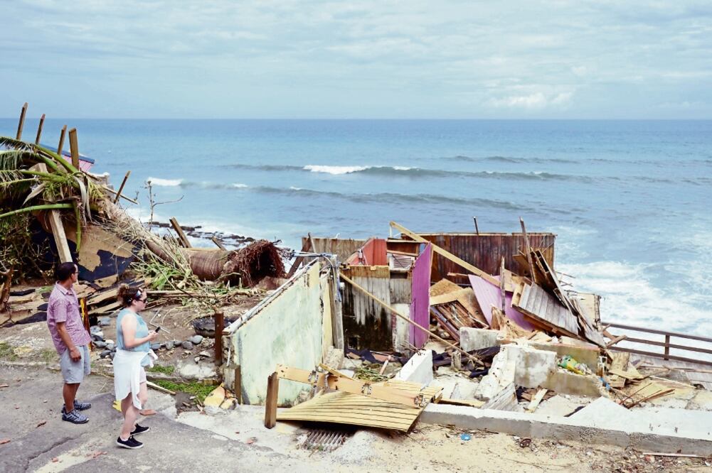 Las personas miran un edificio destruido por el huracán María en la comunidad de La Perla en Viejo San Juan, Puerto Rico. (CARLOS GIUSTI. AP)
