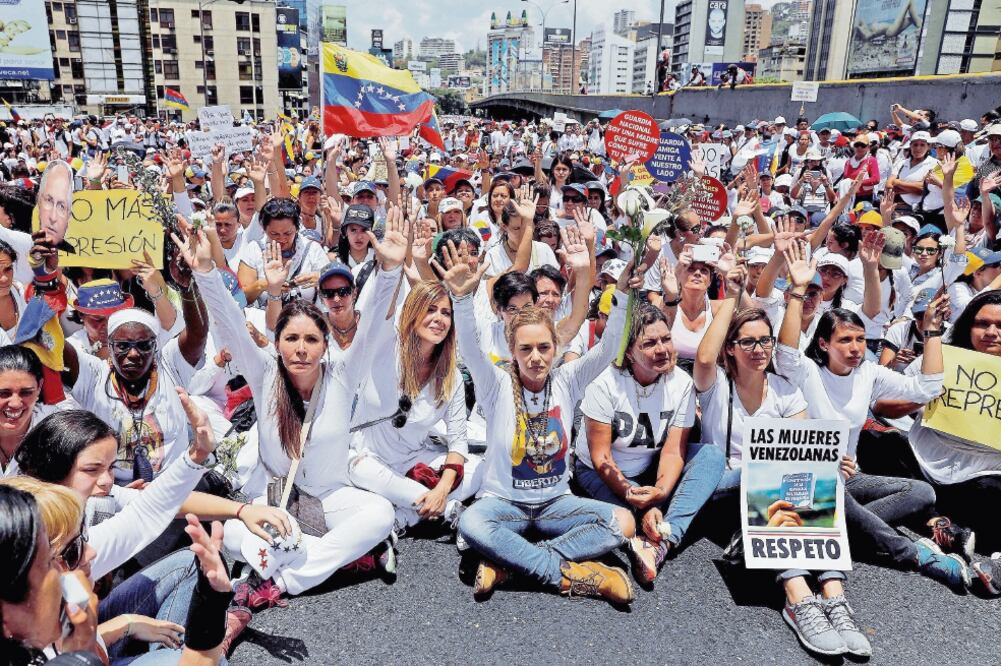 Las manifestantes, quienes en su mayoría vestían de blanco, protestaron contra las políticas impulsadas por el presidente Nicolás Maduro. (CARLOS GARCÍA. REUTERS)