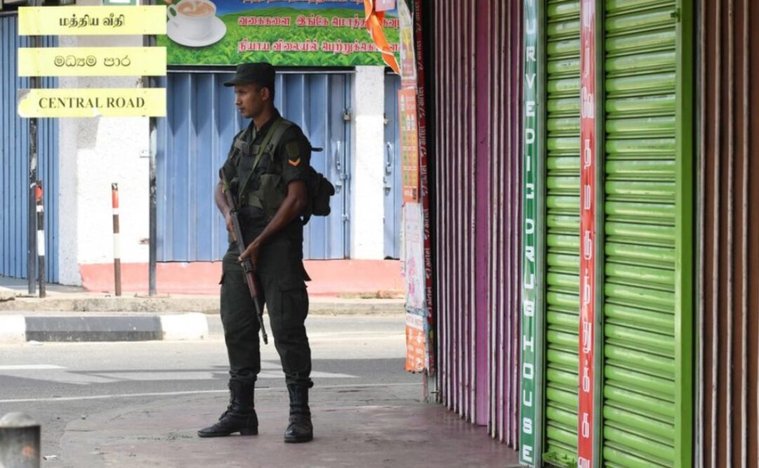 Un soldado srilankés hace guardia frente a un conjunto de tiendas cerradas en Batticaloa, al este del país (Foto: AFP)