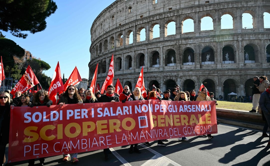 La gente marcha detrás de una pancarta que dice "Dinero para salarios, no para armamentos" cerca del Coliseo durante una jornada nacional de huelga del sindicato italiano "Confederazione Generale Italiana del Lavoro" (CGIL) contra la ley de presupuesto del gobierno, el 12 de diciembre de 2025. Foto: AFP