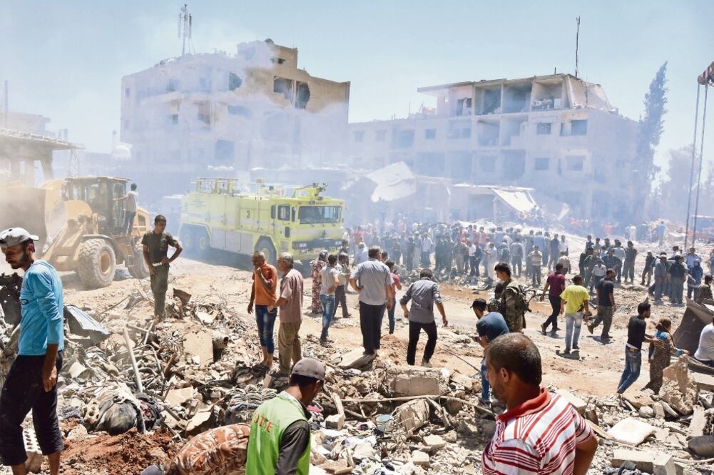 Lugareños se reúnen en el sitio donde ocurrieron dos explosiones, reivindicadas por el EI, en el pueblo sirio de Qamishli (RODI SAID. REUTERS)