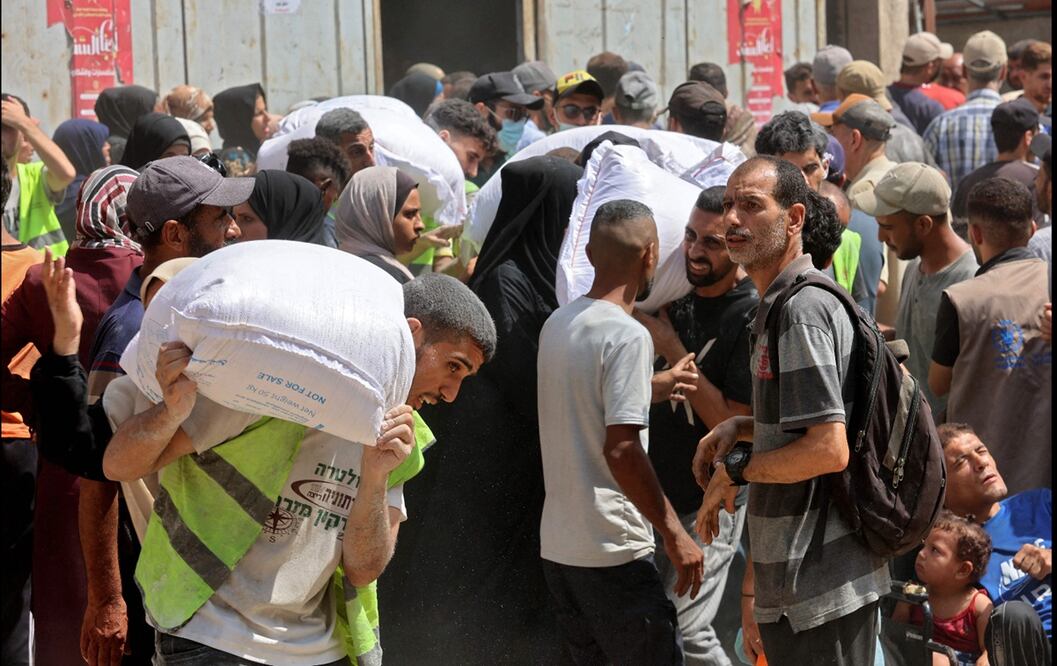 Palestinos llevan bolsas de ayuda de un almacén del Programa Mundial de Alimentos (PMA) de la ONU, el 12 de julio de 2025. Foto: Archivo/AFP