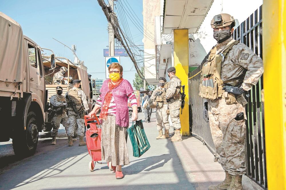 Una mujer realiza compras en una tienda de abarrotes mientras en un televisor aparece el presidente de Nicaragua, Daniel Ortega, durante una transmisión de Cadena Nacional en Managua.