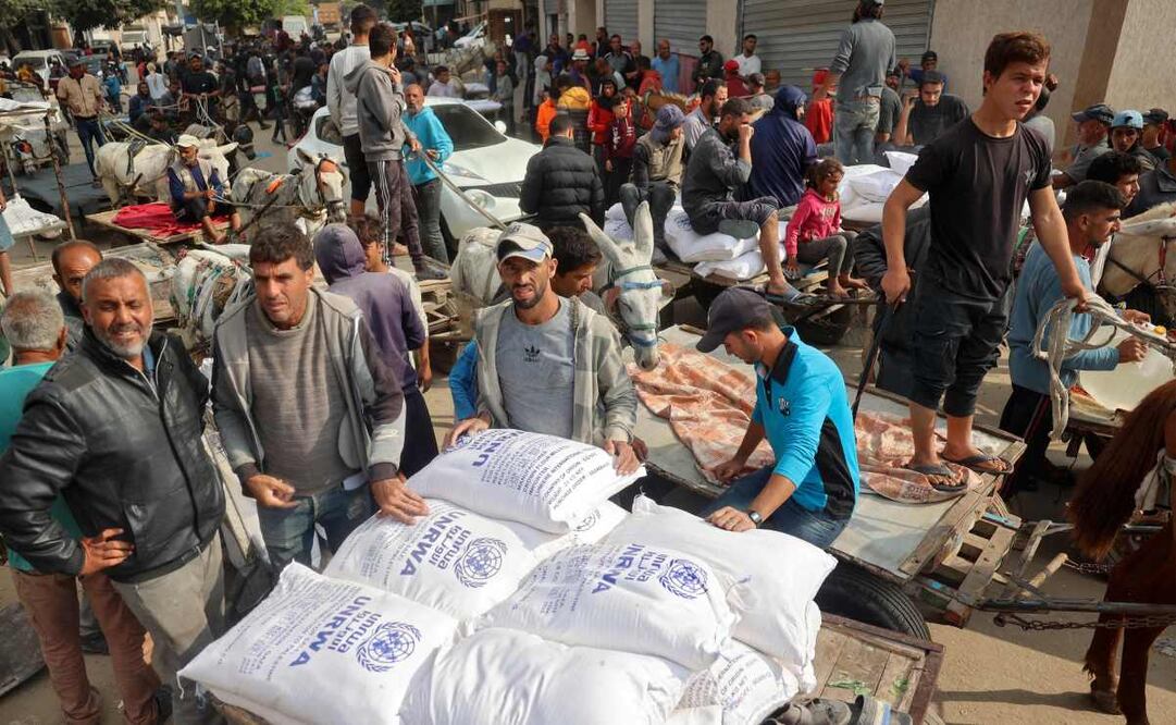 La gente carga sus carros con sacos de harina en un centro de distribución de ayuda de la Agencia de Obras Públicas y Socorro de las Naciones Unidas (UNRWA) en Deir el-Balah el 4 de noviembre de 2024, en medio de la guerra en curso entre Israel y el grupo militante palestino Hamás. Foto: AFP