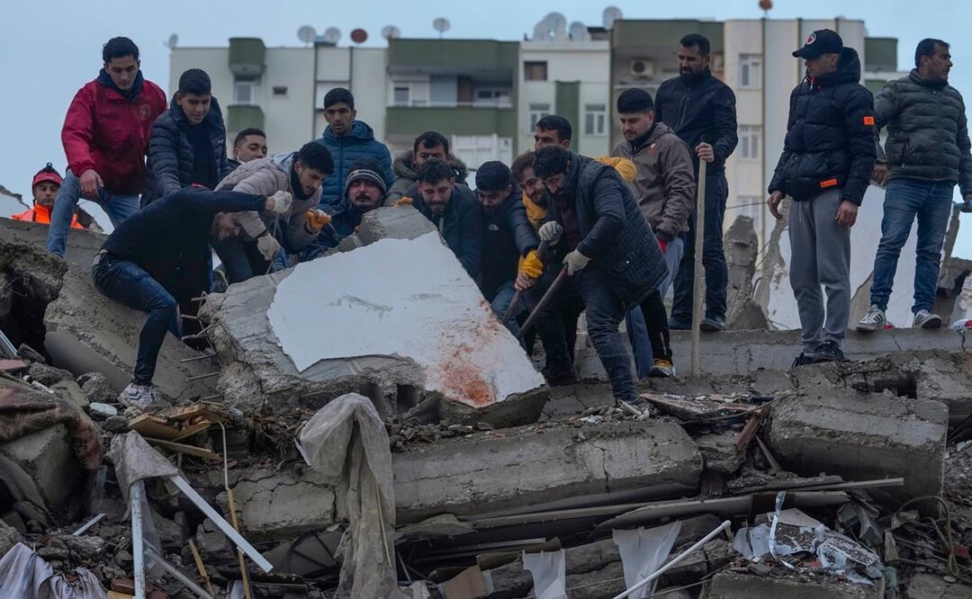 Un grupo de personas busca entre los escombros de un edificio a sobrevivientes tras un sismo, en Adana, Turquía. Foto: AP