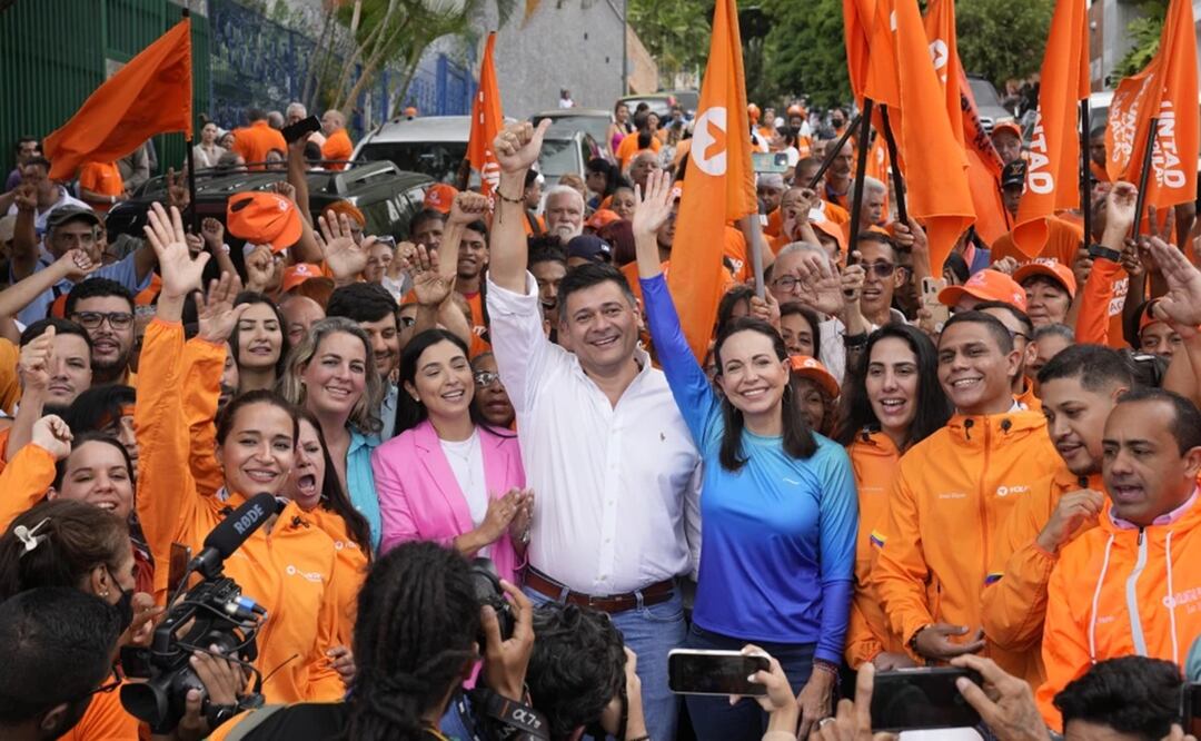 La aspirante presidencial de la oposición María Corina Machado y el líder opositor Freddy Superlano, ambos al centro, levantan los brazos para los fotógrafos durante un evento de campaña en Caracas, Venezuela. Foto: AP