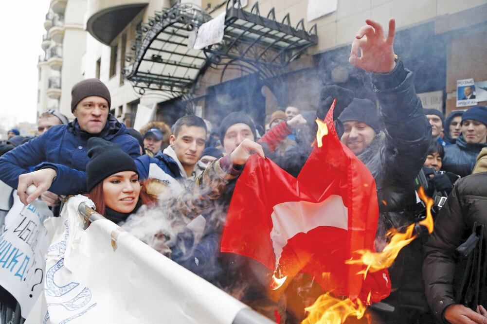 Manifestantes rusos queman una bandera turca mientras protestan delante de la Embajada de Turquía en Moscú, tras el derribo, el martes, de un avión Su-24 (MAXIM SHIPENKOV. EFE)