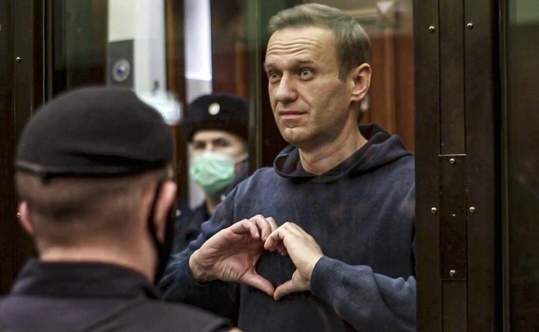El líder opositor ruso Alexei Navalny hace un corazón con sus manos desde el espacio reservado para los acusados durante una vista en el tribunal, en Moscú. Foto: AP