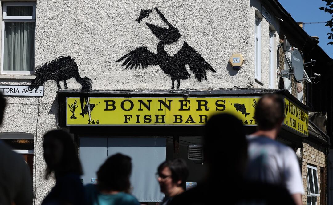 La gente ve una obra de arte de Banksy recientemente confirmada en el lado de una tienda de pescado y patatas fritas en Walthamstow, Londres, Gran Bretaña. Foto: EFE/EPA/ANDY RAIN.