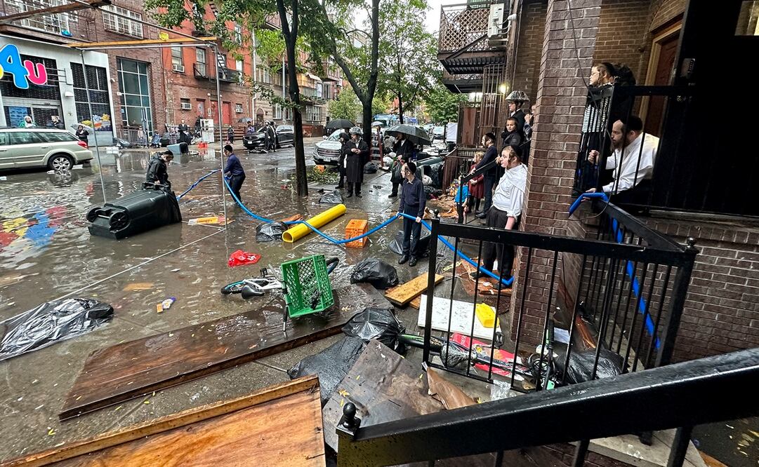 Los residentes observan cómo los trabajadores intentan limpiar un drenaje, en el distrito de Brooklyn de Nueva York. Foto: AP