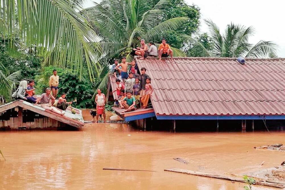 Un grupo de personas aguarda en lo alto de un tejado en una zona inundada tras el derrumbe de una presa hidroeléctrica en Laos. (EFE)