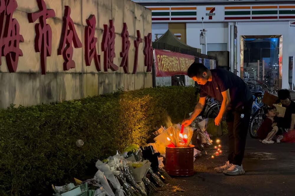 Un hombre enciende una vela cerca de unas flores colocadas en el exterior del "Zhuhai People's Fitness Plaza", donde un hombre embistió deliberadamente con su coche a unas personas que se ejercitaban en el centro deportivo, matando a algunas y hiriendo a otras en Zhuhai, en la provincia de Guangdong, en el sur de China, el 12 de noviembre de 2024. FOTO: NG HAN GUAN. AP