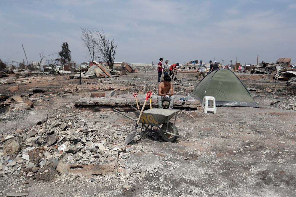 Personas del campamento irregular Pompeya recogen escombros, tras los incendios del día viernes 2 de febrero, en la zona de Viña del Mar. Foto: EFE