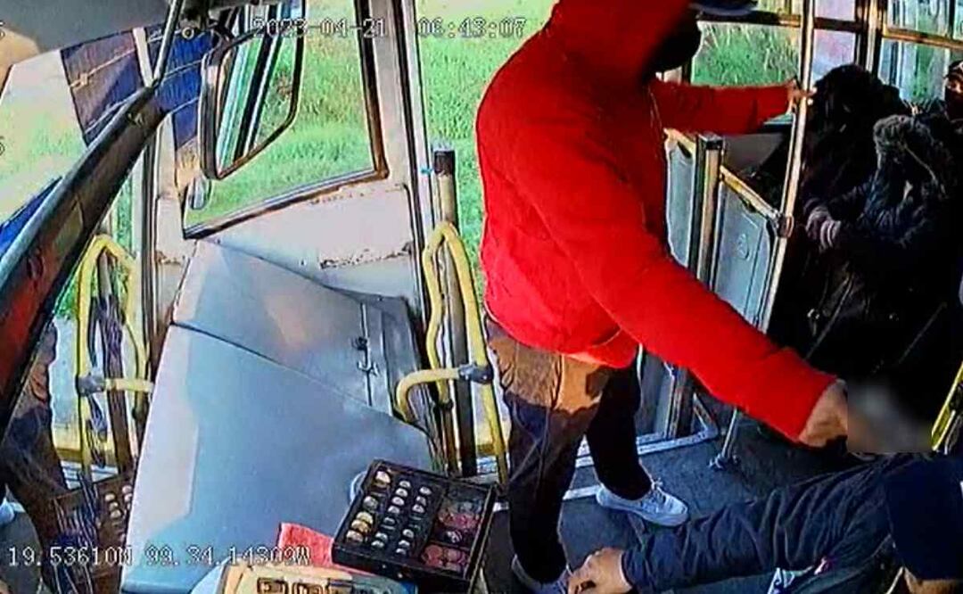 Uno de los delincuentes se mantiene junto al conductor, lo amaga con un arma de fuego para que detenga la marcha Foto: Captura de video