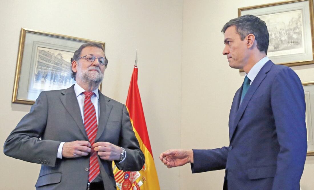 El presidente del gobierno español en funciones, Mariano Rajoy se abrocha el saco mientras el secretario general del PSOE, Pedro Sánchez, le tiende la mano, en Madrid (EFE)