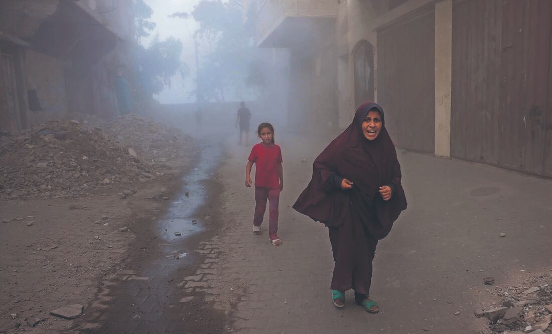 Una palestina y sus hijos huyen de los ataques aéreos israelíes contra un edificio al oeste de Jabalia, en el norte de la Franja de Gaza. Foto: de BASHAR TALEB. AFP