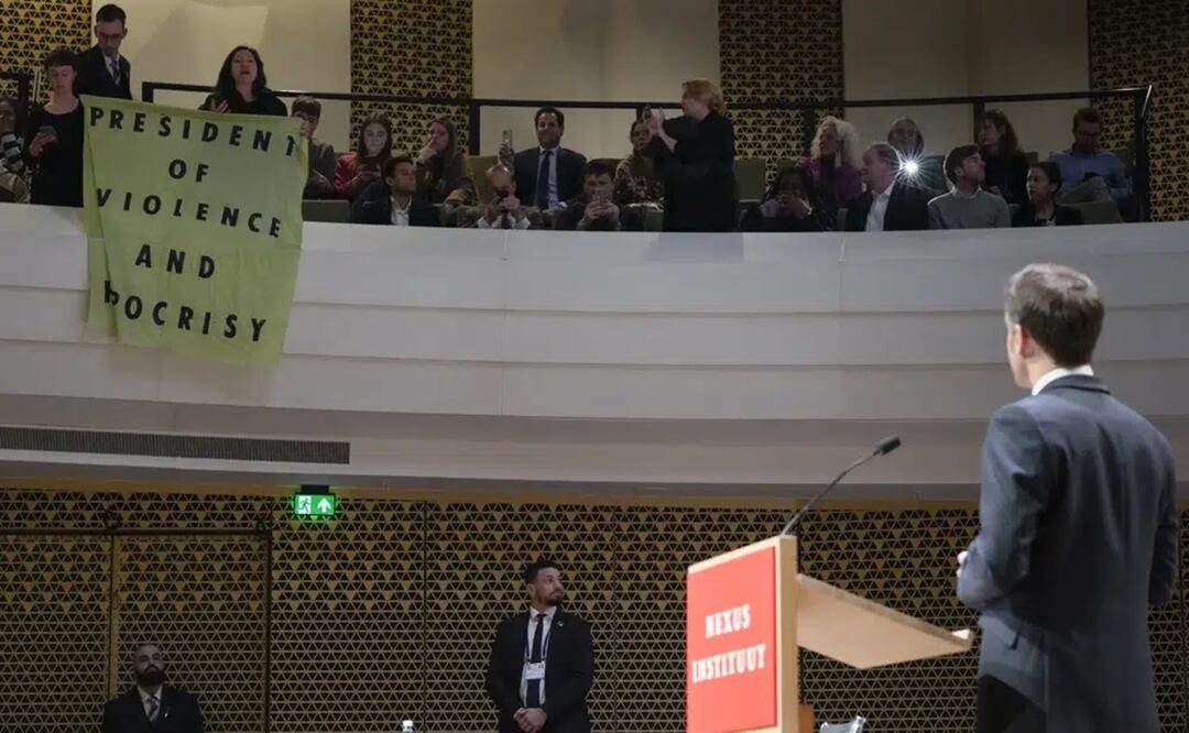 El presidente francés Emmanuel Macron mira a los manifestantes que despliegan una pancarta que dice "Presidente de la violencia y la hipocresía" mientras explica su visión sobre el futuro de Europa. Foto: AP