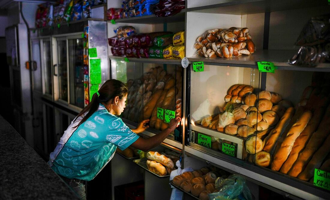 Un trabajador de una panadería ajusta la tienda durante un apagón en Caracas. Foto: AP