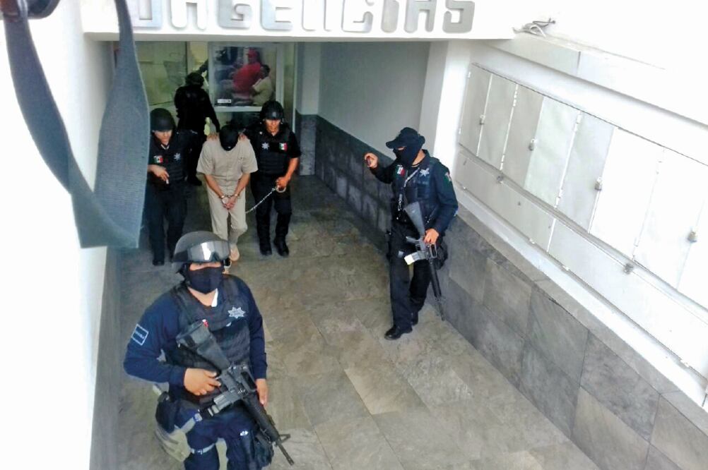 En la fotografía que circuló en medios se observa a un recluso con uniforme gris, esposado y el rostro cubierto con una capucha; caminaba escoltado por cuatro elementos de la Policía Federal que portaban armas de grueso calibre (CORTESÍA)