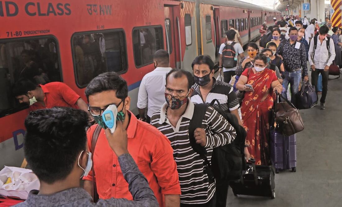 Un empleado sanitario revisa la temperatura de un pasajero en una estación de tren en Bombay. Foto: Rajanish Kakade. AP