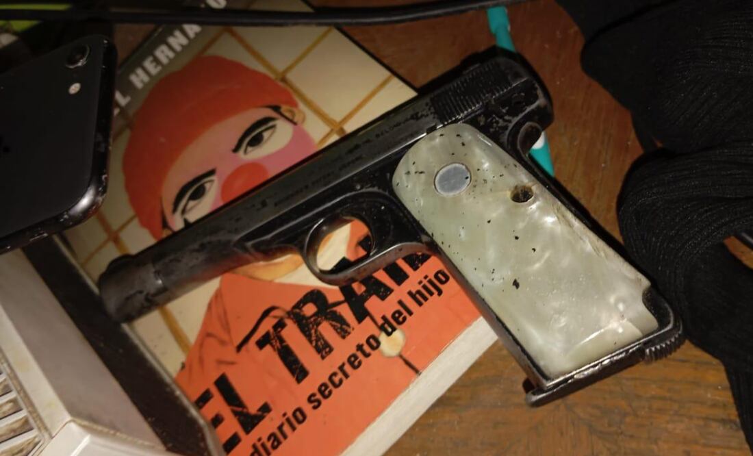 Al interior aseguraron un arma de fuego corta color gris con blanco con un cargador vacío, encima del libro de la periodista Anabel Hernández (30/10/2024) . Foto: Especial