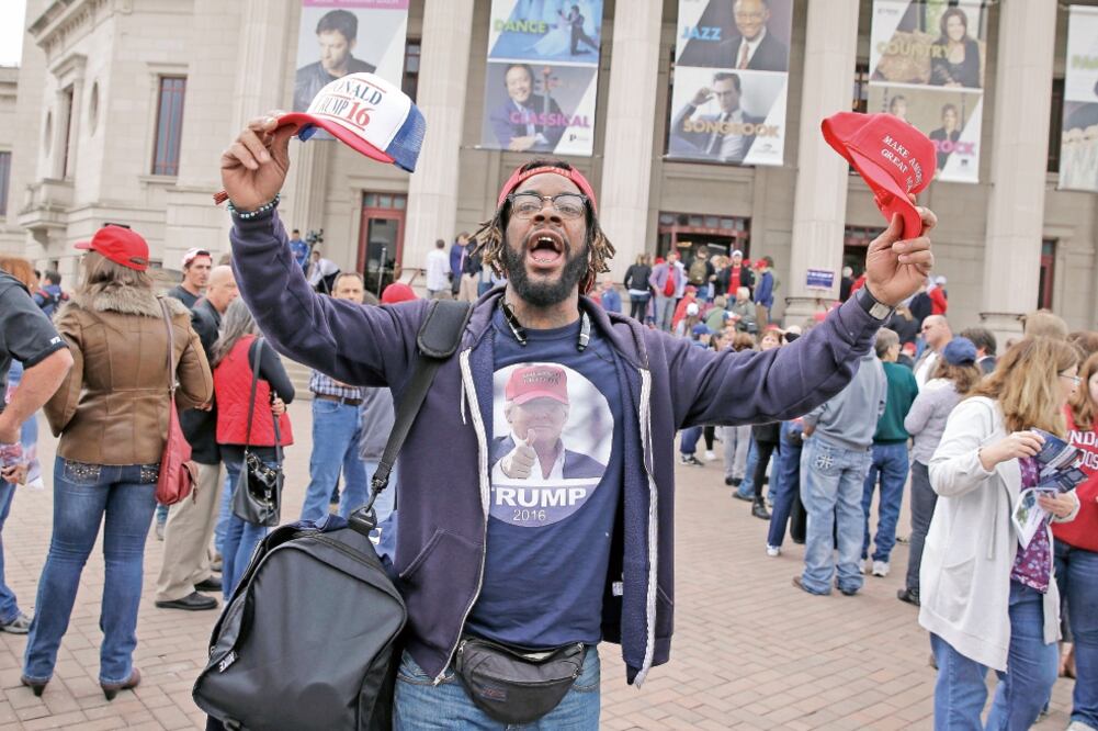 Un afroestadounidense vendiendo ayer en Indiana camisetas y gorros de Donald Trump, precandidato republicano a la Casa Blanca (MICHAEL CONROY. AP)