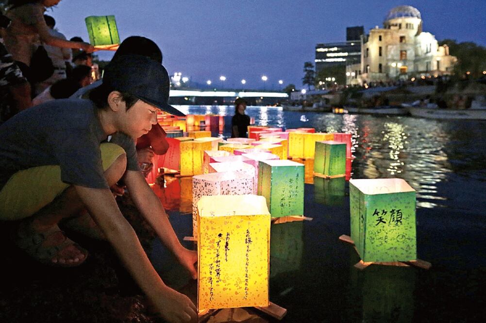 Personas colocan linternas de papel junto al río Motoyasu, en memoria de las víctimas de la bomba atómica en el Parque de la Paz de Hiroshima, en el 70 aniversario del ataque a la ciudad japonesa (KIYOSHI OTA. EFE)
