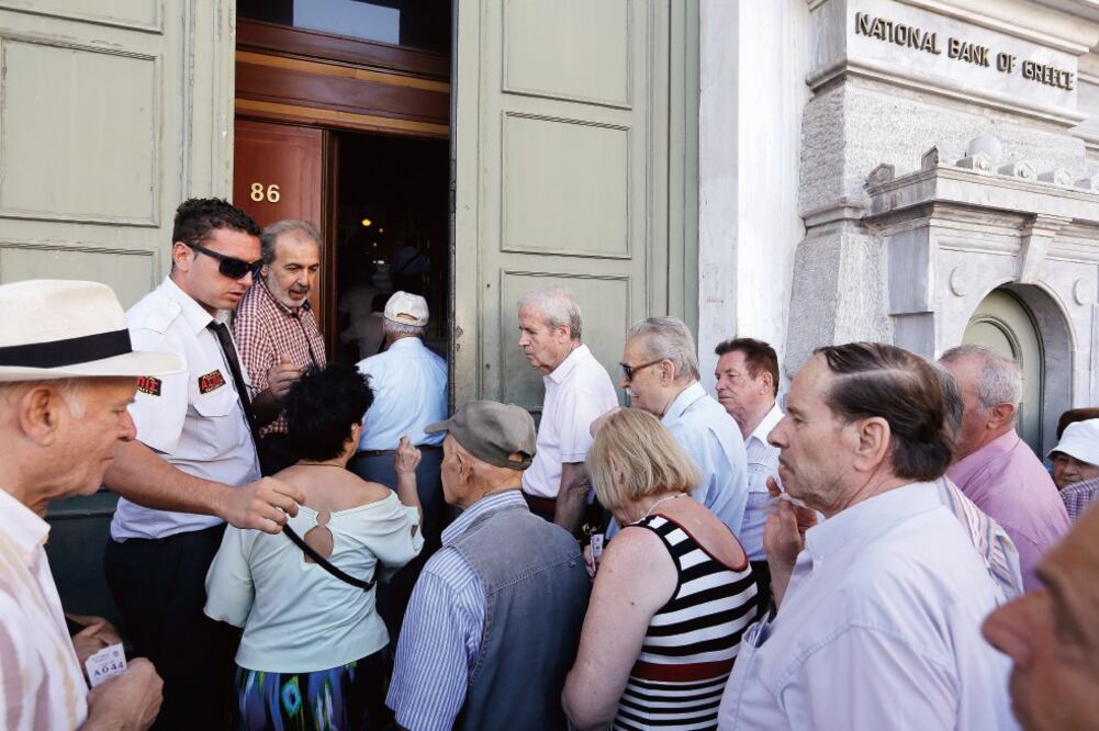 Los griegos hacen fila desde muy temprano en el Banco Nacional de Grecia y en otras entidades bancarias, que ayer reabrieron sus puertas. (THANASSIS STAVRAKIS. AP)