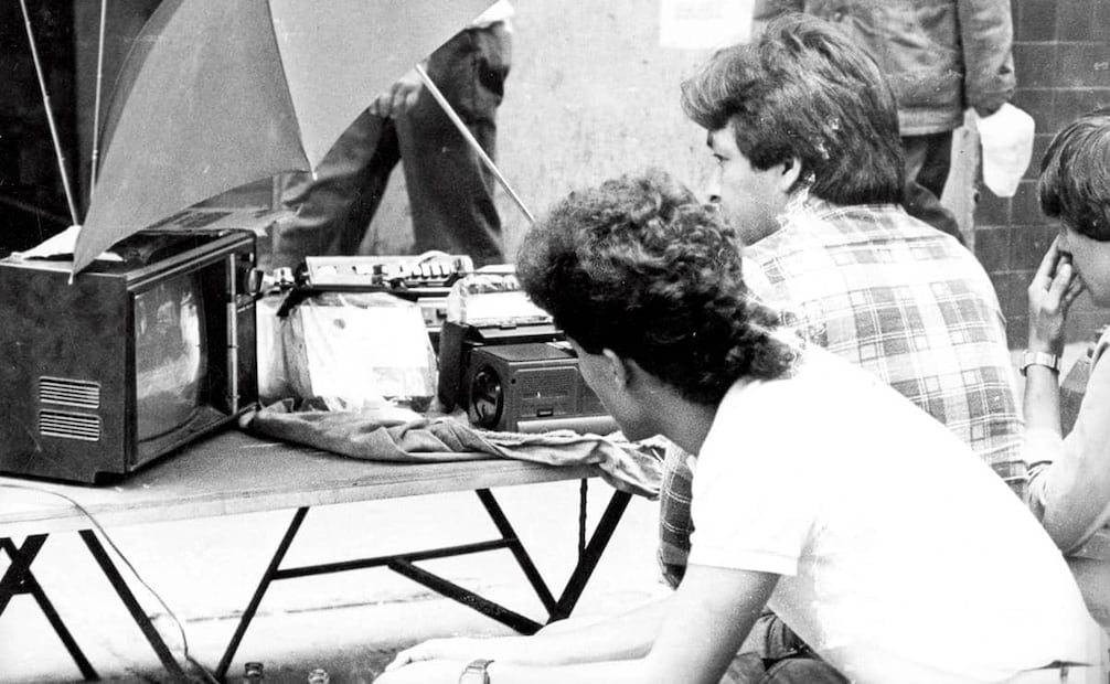 Vendedores de fayuca en República del Salvador, usando su propia mercancía para ver el partido México vs. Bélgica, 3 de junio 1986. En ese entonces, no sólo se vendía una televisión según su calidad de imagen o sonido; también importaba si tenía manija para transportarse, pues muchos mexicanos solían sacar sus aparatos para ver el mundial con vecinos o amigos. Foto: Archivo EL UNIVERSAL.